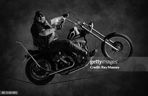 'hell's angel' riding motorcycle on tightrope (b&w) - moto humour photos et images de collection