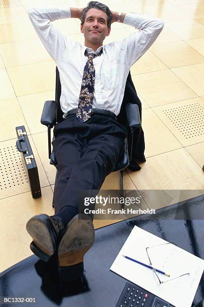 executive leaning back in chair, feet on table, elevated view - hands behind head stock pictures, royalty-free photos & images