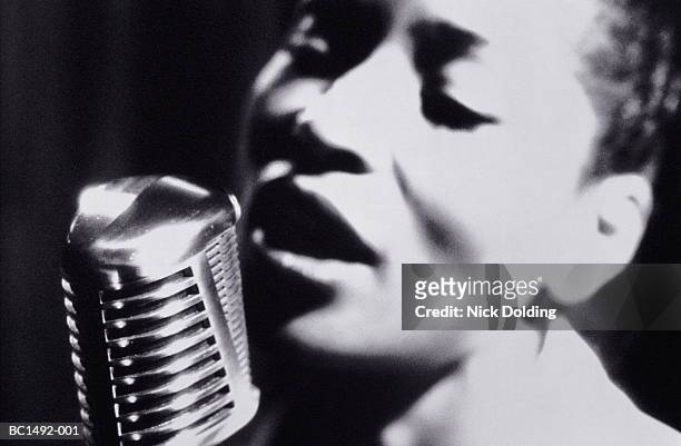 woman singing into microphone, close-up (b&w) - zangeres stockfoto's en -beelden