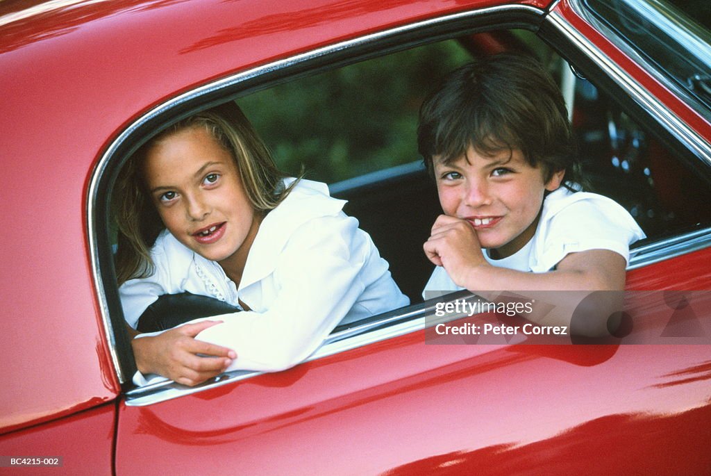 Boy and girl (6-10) sitting in car, looking out of window, portrait