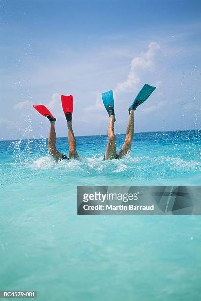 two men diving, legs with flippers above water - ダイビング用のフィン ストックフォトと画像