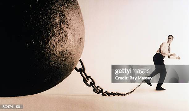 male executive with large ball and chain attached to ankle (toned b&w) - handboeien stockfoto's en -beelden