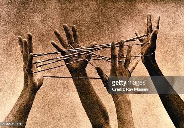 four hands connected by cord, forming 'cat's cradle' (toned b&w) - four people foto e immagini stock