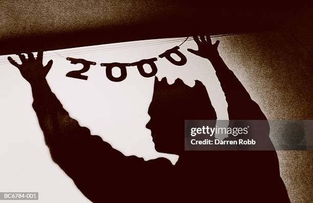 man wearing party hat, putting up year 2000 decoration (toned b&w) - the millennium stockfoto's en -beelden