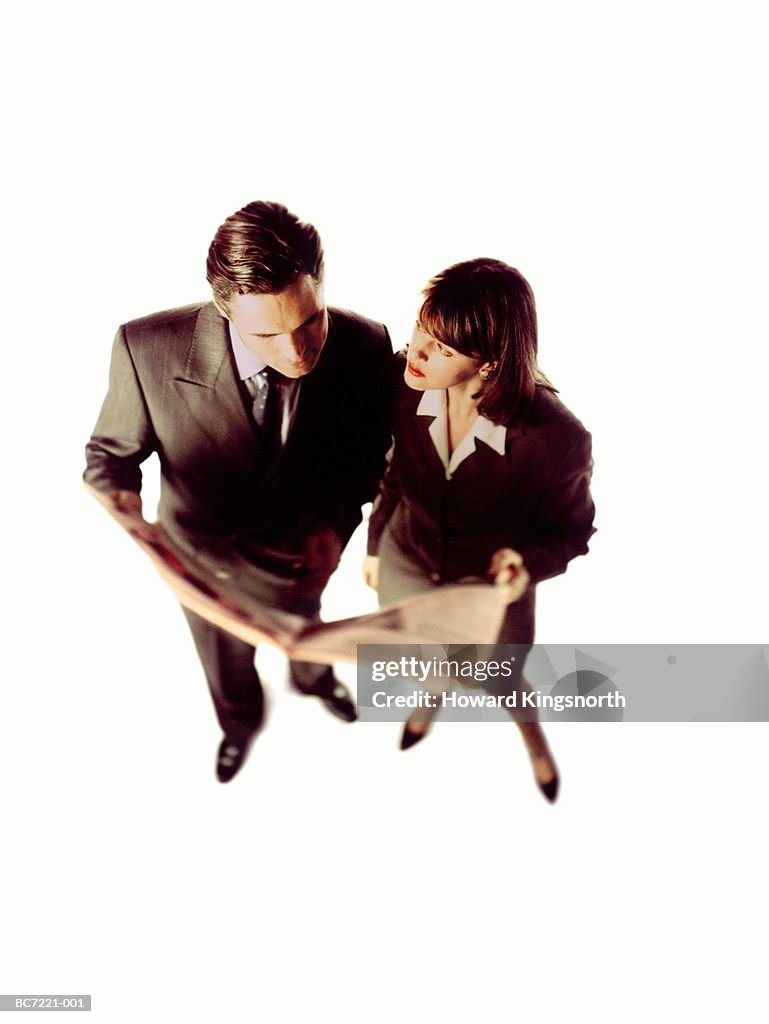 Male and female executives looking at newspaper, elevated view