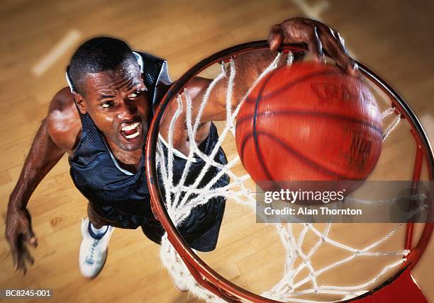 basketball player jumping below basket, elevated view (enhancement) - mate de baloncesto fotografías e imágenes de stock