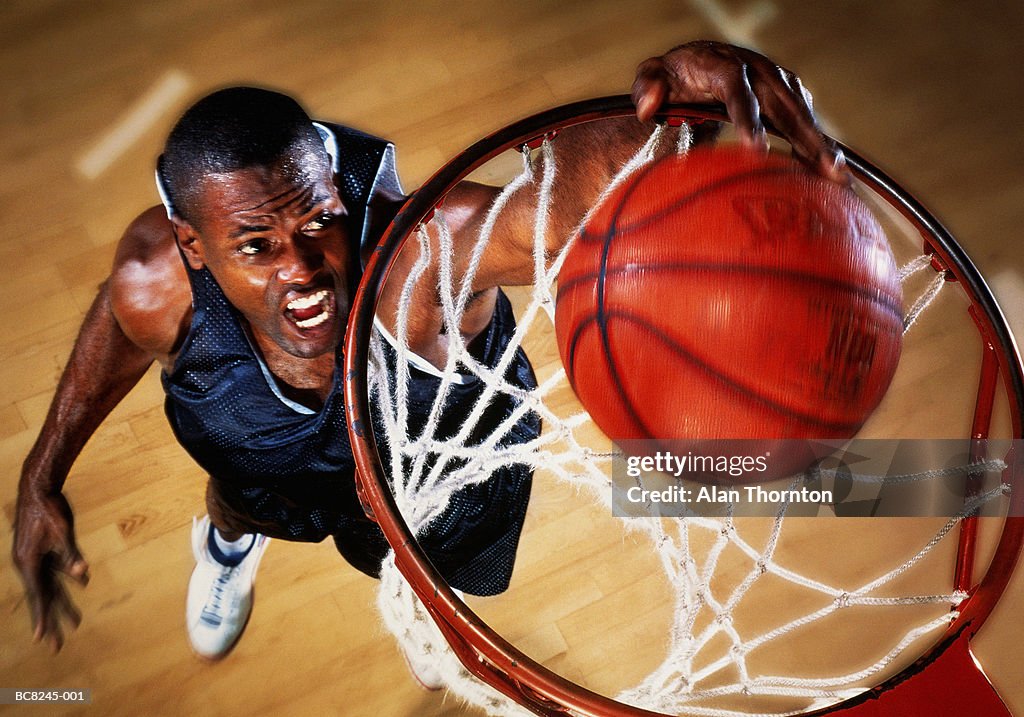 Basketball player jumping below basket, elevated view (Enhancement)