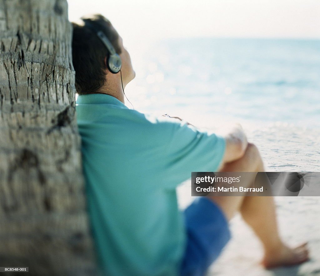 Man sitting on beach wearing headphones