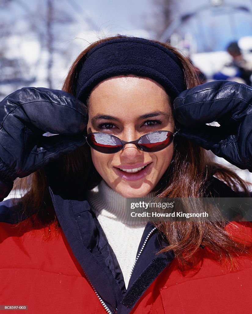 Young woman in winter clothing, holding sunglasses, portrait
