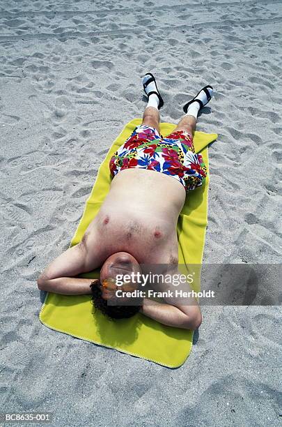 overweight man lying on towel on beach, sunbathing, elevated view - fat guy on beach fotografías e imágenes de stock