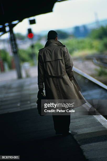 male executive standing on railway station platform, rear view - trench coat stock pictures, royalty-free photos & images