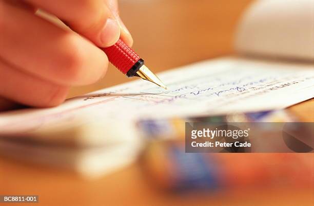 woman's hand writing cheque, close-up - assegno foto e immagini stock