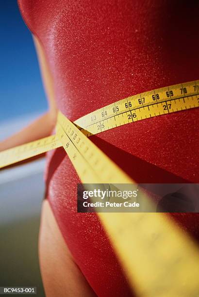 teenage girl (13-15) measuring waist with tape measure, close-up - waist stockfoto's en -beelden