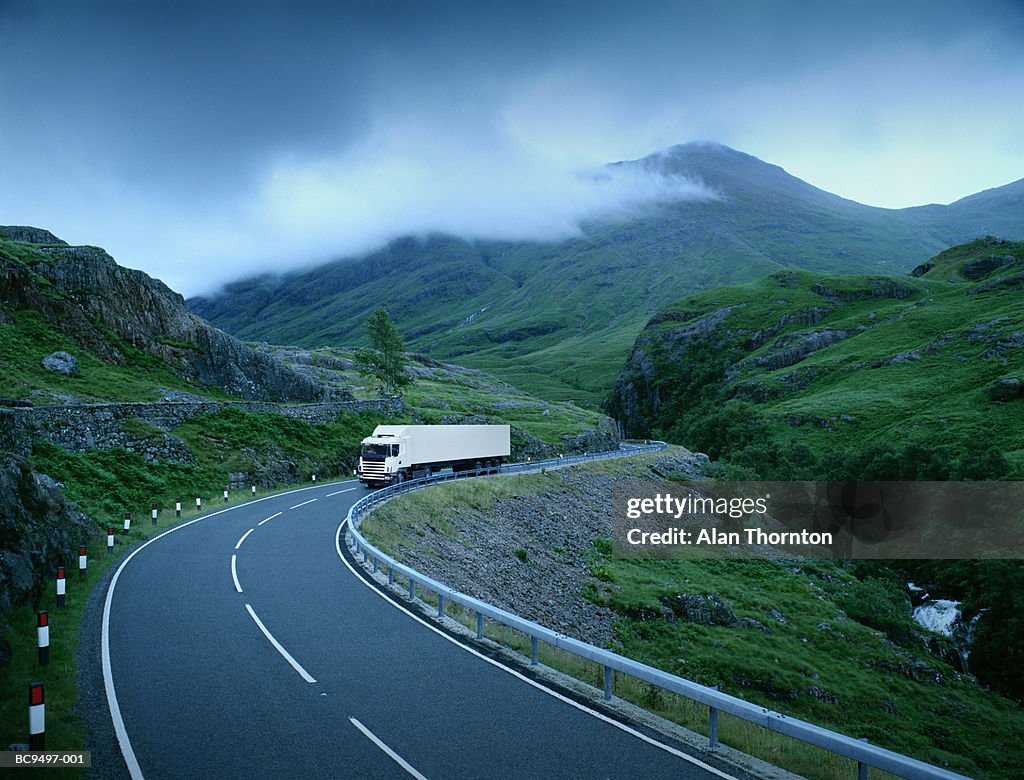 White lorry on road through rural landscape (Digital Composite)
