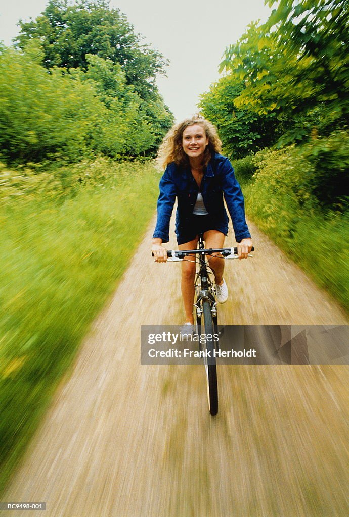 Young woman cycling along country lane (blurred motion)