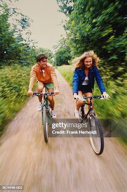 young couple cycling along country lane (blurred motion) - bicycle lane stock-fotos und bilder