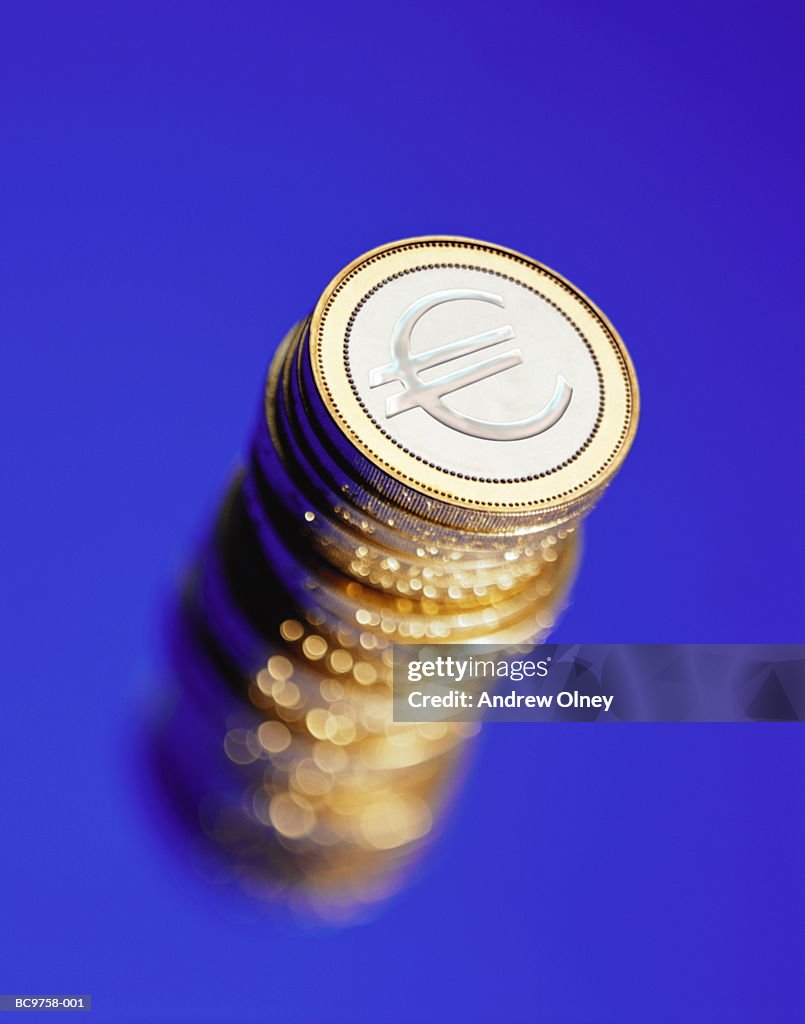 Pile of Euro coins against blue background, elevated (Composite)