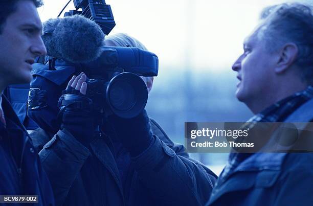 television crew interviewing mature man, outdoors - periodista de televisión fotografías e imágenes de stock