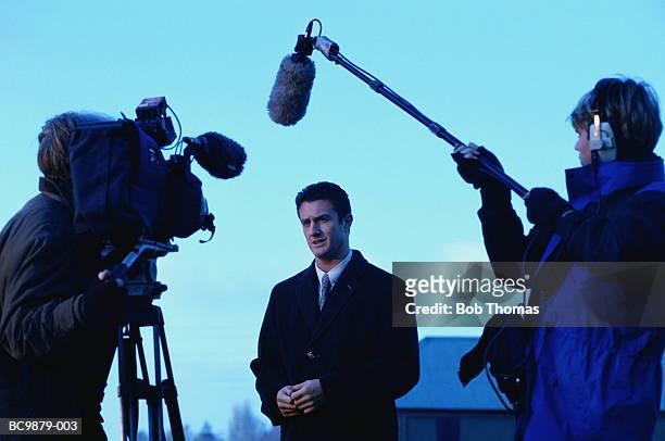 television reporter talking to camera, outdoors at dusk - cameraman photos et images de collection