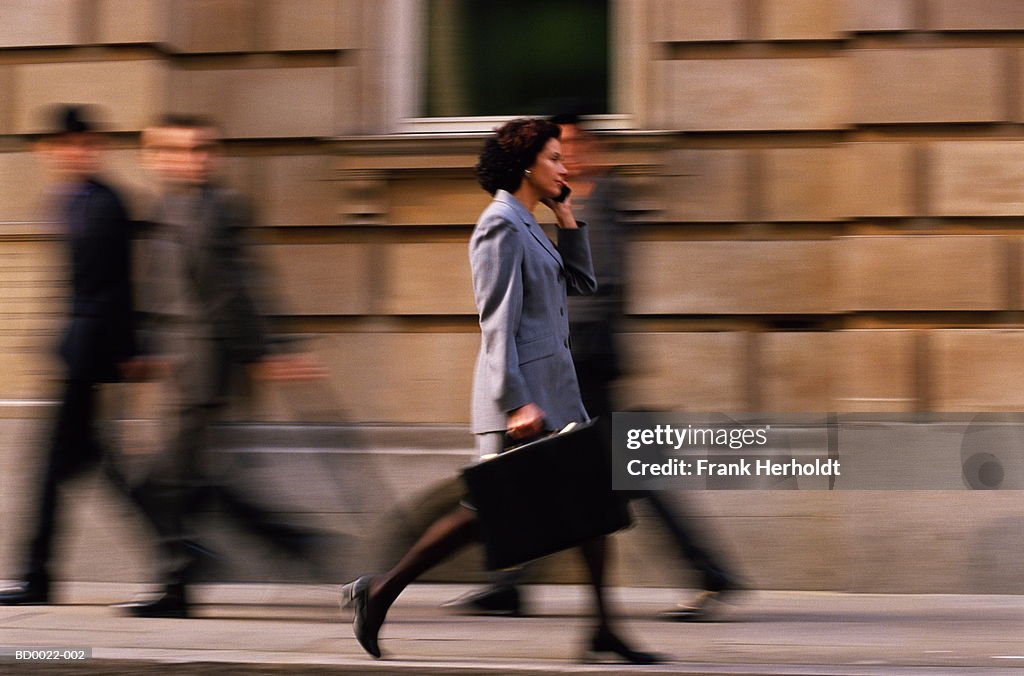 Female executive walking, using mobile phone (blurred motion)