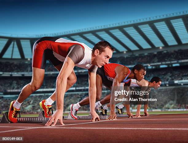 male athletes poised on starting blocks (digital composite) - estadio de atletismo fotografías e imágenes de stock