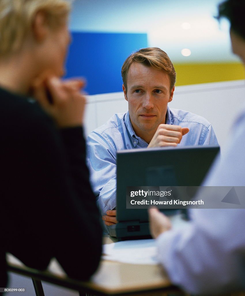 Three executives sitting around desk, talking, close-up