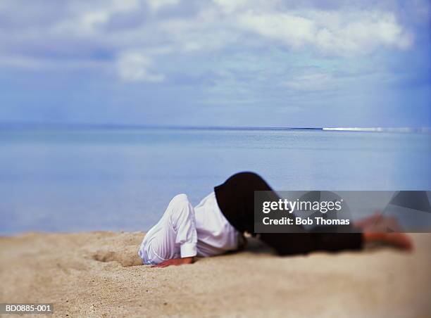 businessman with head in sand, sea in background - midlife crisis stock pictures, royalty-free photos & images