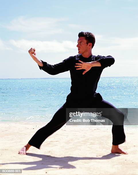 young man doing tai chi on beach - tai chi imagens e fotografias de stock