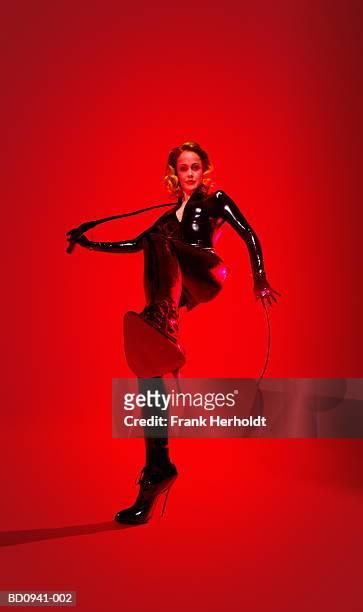young woman wearing bodysuit, holding whip, kicking (enhancement) - servidão imagens e fotografias de stock