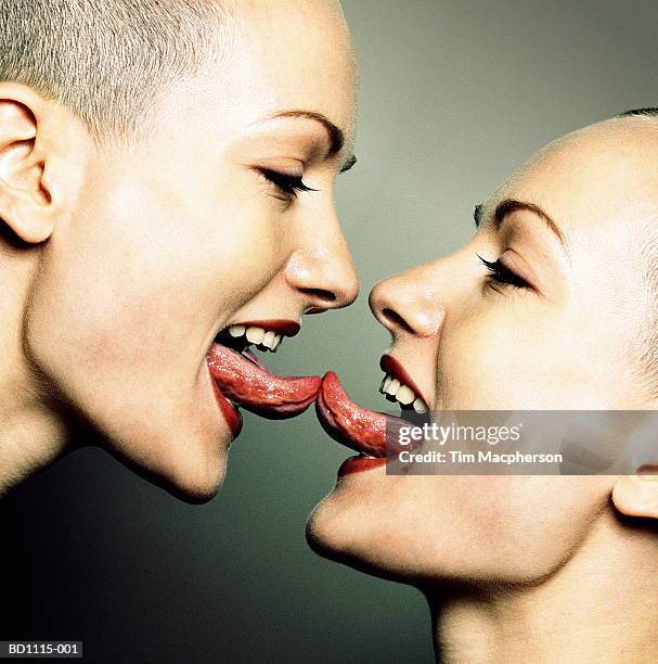 two young women with tongues touching, profile (composite) - sticking tongue out profile photos et images de collection