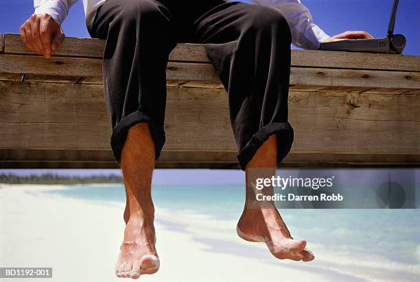 businessman using laptop on jetty at beach, close-up of bare feet - mens bare feet fotografías e imágenes de stock