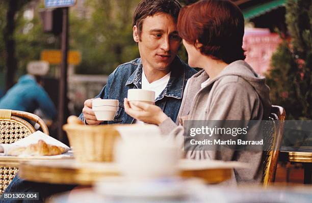 young couple drinking coffee at outdoor cafe, paris, france - französisch sprache stock-fotos und bilder