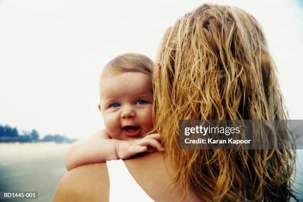 mother and baby girl (6-9 months) on beach, view over shoulder - over the shoulder carry stock pictures, royalty-free photos & images