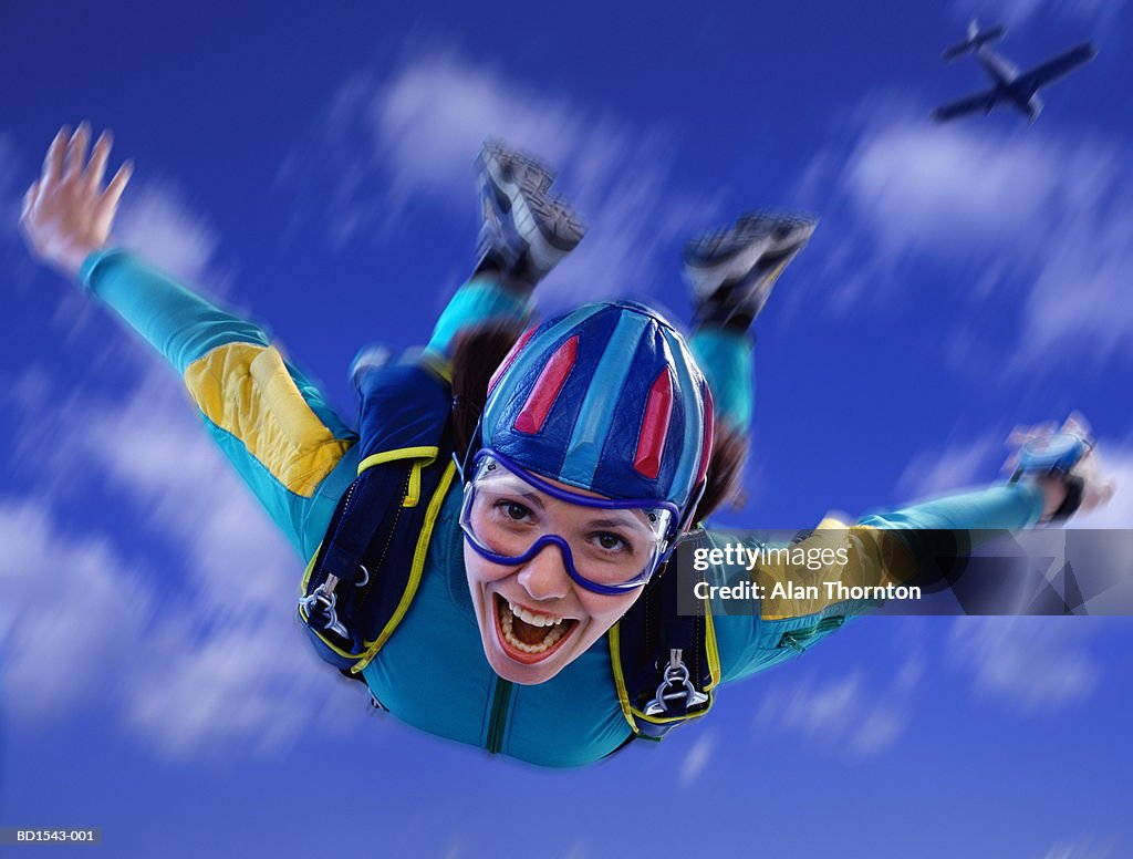 Young woman skydiving, close-up, low angle view (Digital Composite)
