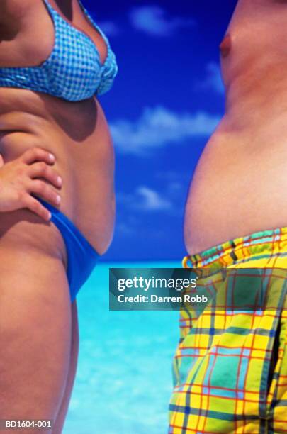 couple on beach, facing each other, close-up of torsos - zwembroek stockfoto's en -beelden