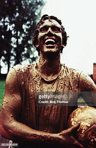 young man covered in mud, holding football, close-up - people covered in mud stock pictures, royalty-free photos & images