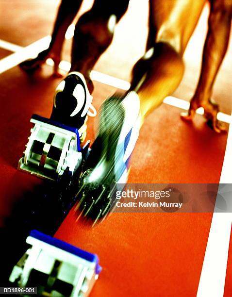 male athlete leaving starting block,low section (blurred motion) - baanevenement mannen stockfoto's en -beelden