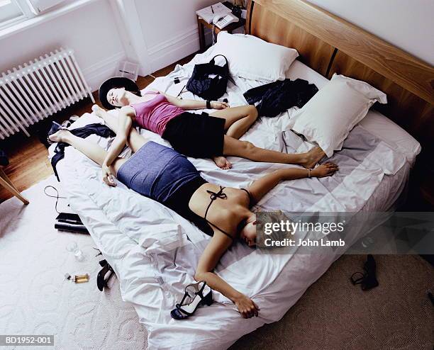 two young women lying asleep on bed, fully clothed, elevated view - roupa de discoteca imagens e fotografias de stock