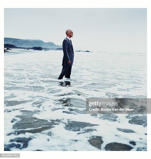 businessman standing in surf - midlife crisis stock pictures, royalty-free photos & images