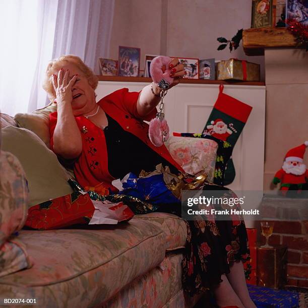 mature woman holding up fluffy handcuffs, hands over face - bad gift stock pictures, royalty-free photos & images