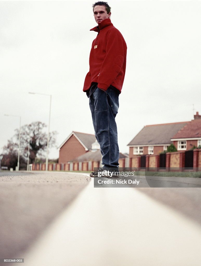 Teenage boy (14-16) standing in street, low angle view