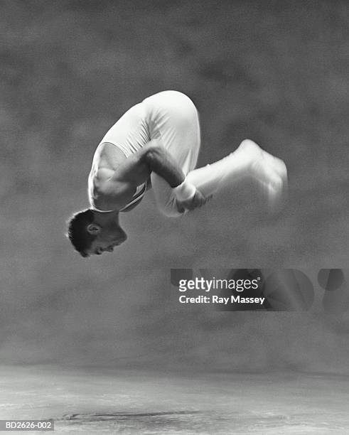 young male gymnast performing somersault (blurred motion, b&w) - somersault stock pictures, royalty-free photos & images