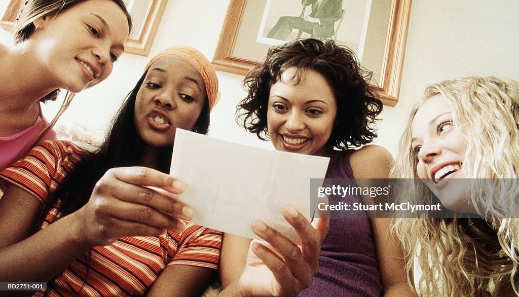 Four young women looking at photograph, low angle view