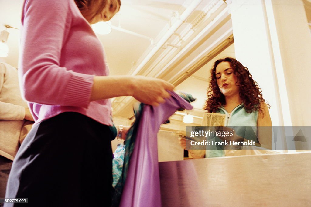 Young woman paying for clothes at shop till, low angle view