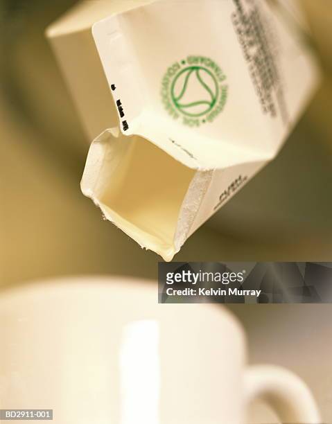 empty milk carton above mug, close-up - milk carton - fotografias e filmes do acervo