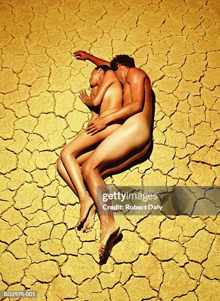 naked young couple lying on cracked mud surface, elevated view - crack spoon stock pictures, royalty-free photos & images