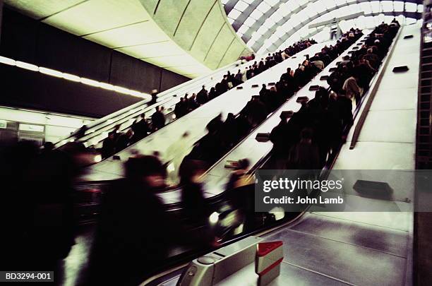 passengers on underground station escalators (blurred motion) - hauptverkehrszeit stock-fotos und bilder