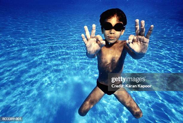 boy (5-7) making okay sign in swimming pool, underwater view - man wearing speedo stock-fotos und bilder