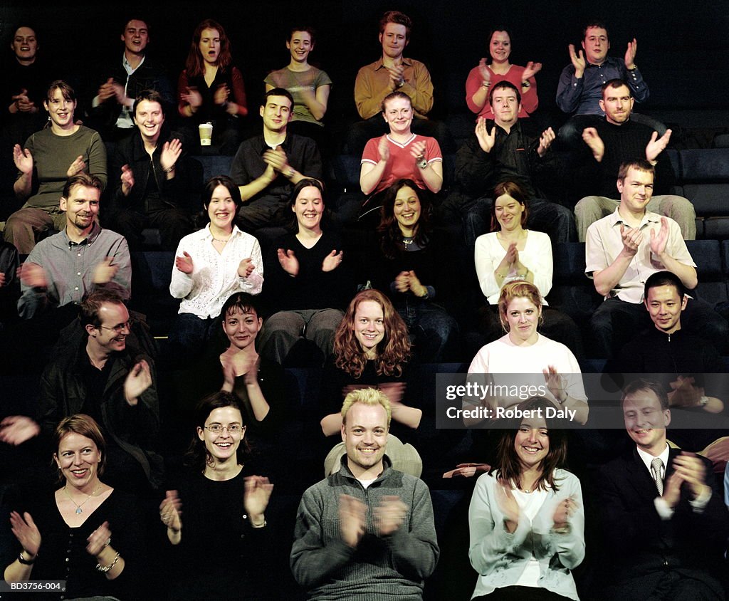 Audience clapping at performance, smiling (blurred motion)