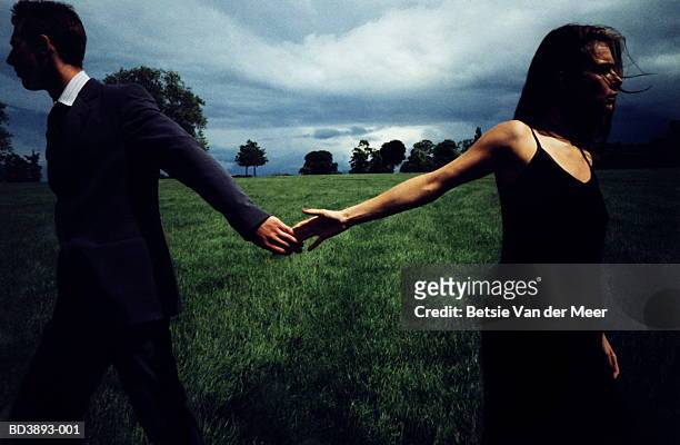 couple in field, letting go of each other's hands - separation foto e immagini stock